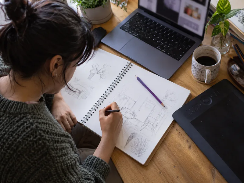 Cuaderno de bocetos junto a un notebook y una tableta gráfica